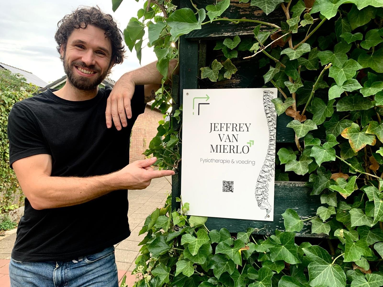 Jeffrey van Mierlo, fysiotherapeut en ketogeen therapeut, bij het bord van zijn praktijk